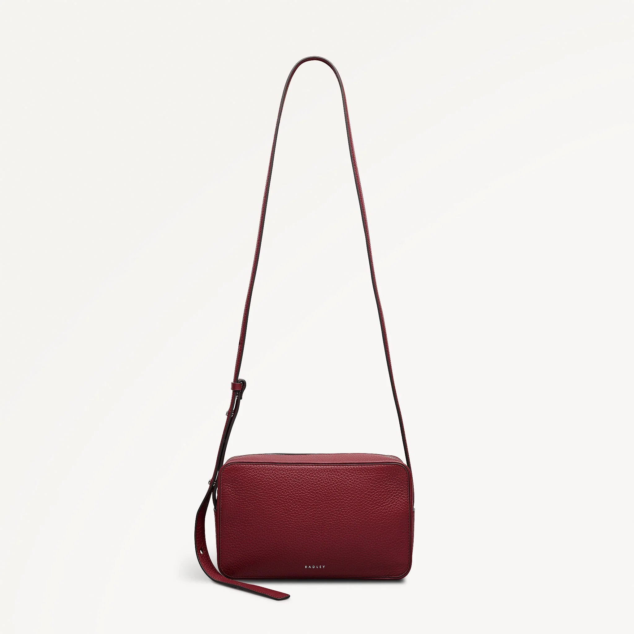 Red handbag with a strap on a light beige background