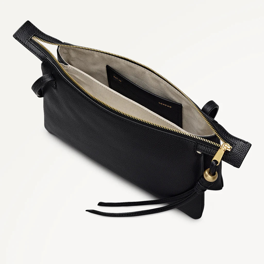 Black leather handbag with gold zipper on a light gray background