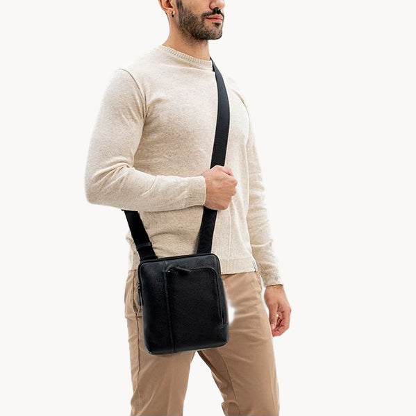 Man holding a black crossbody bag against a white background