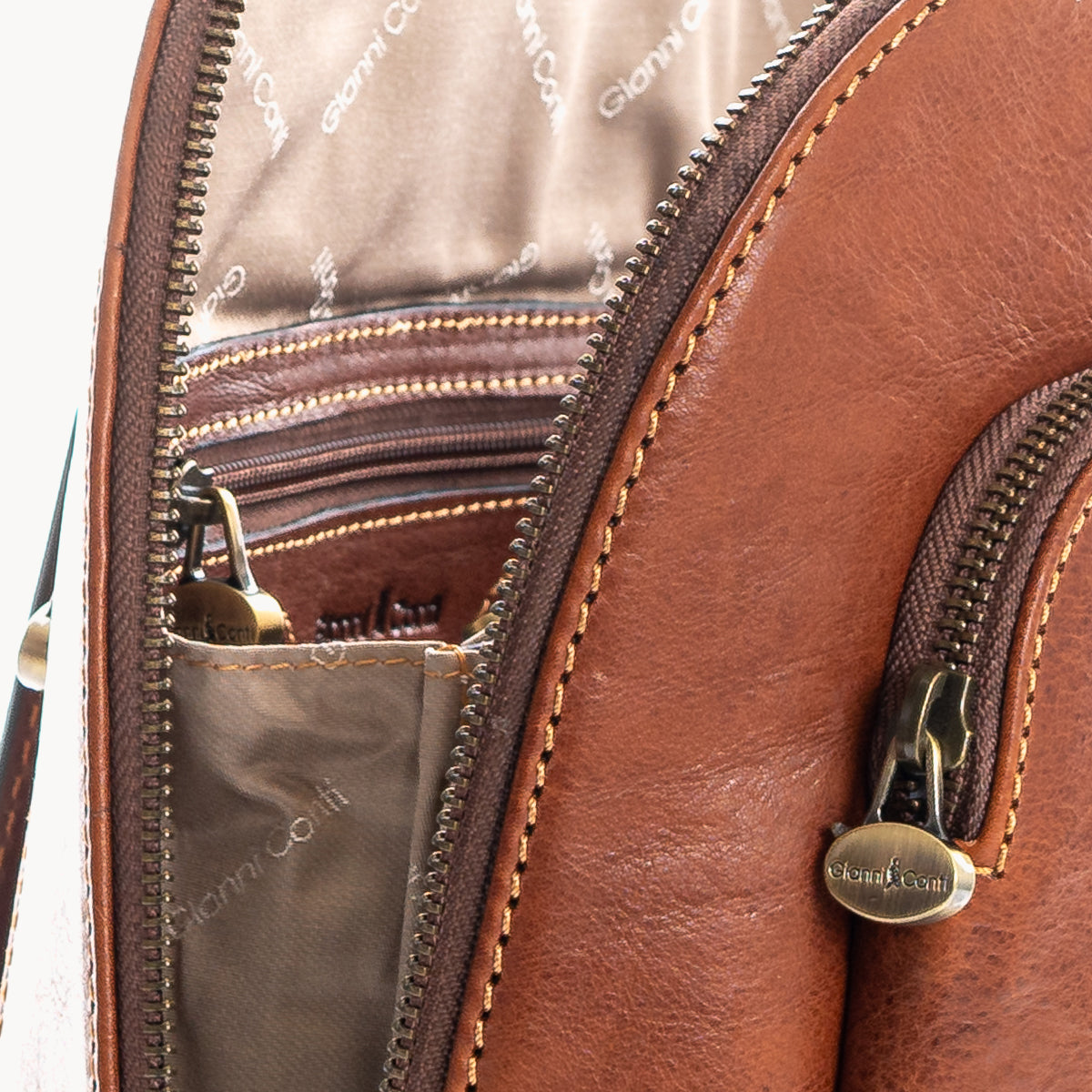 Close-up of a Tan leather bag with gold zipper and stitching details.