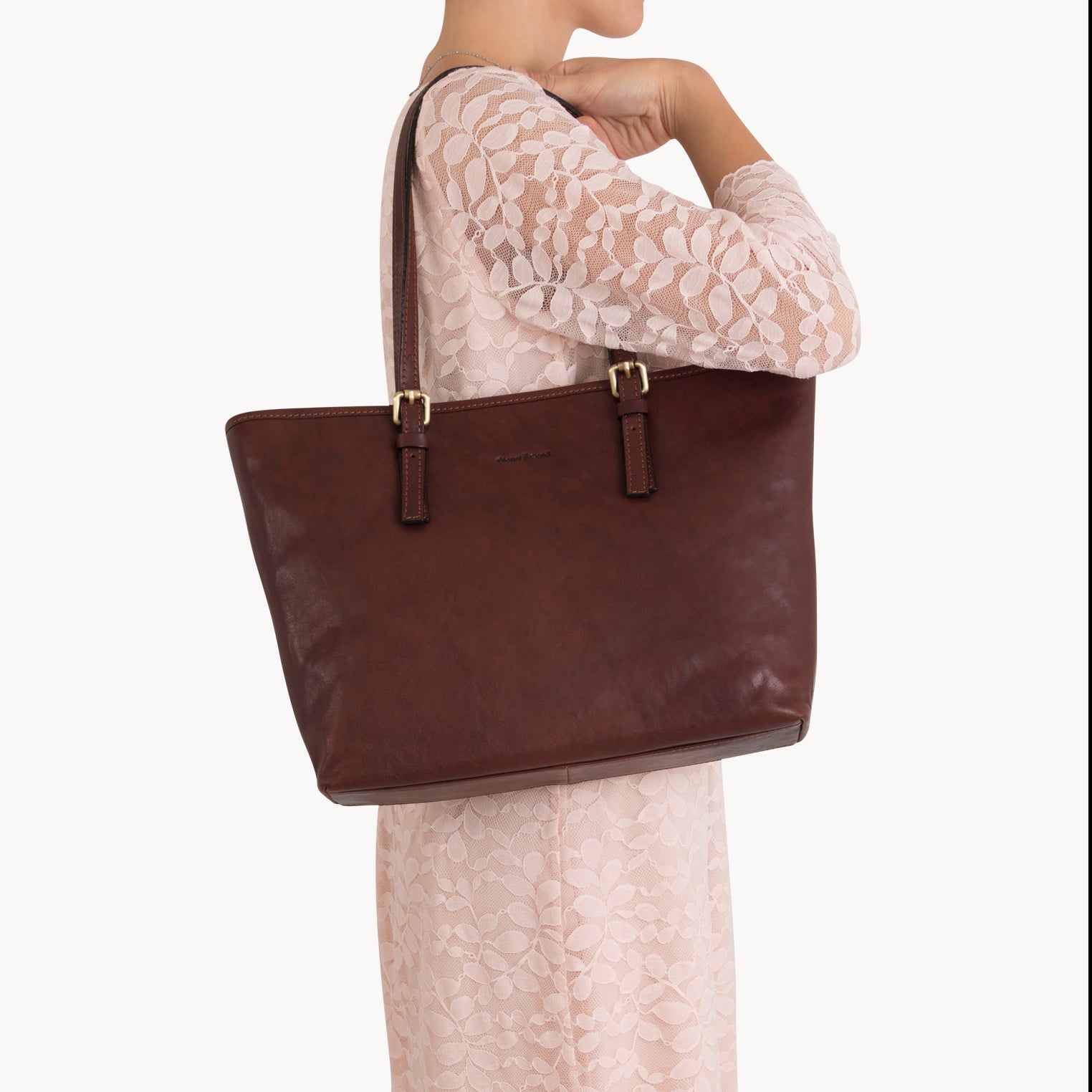 Woman holding a brown leather tote bag on a white background