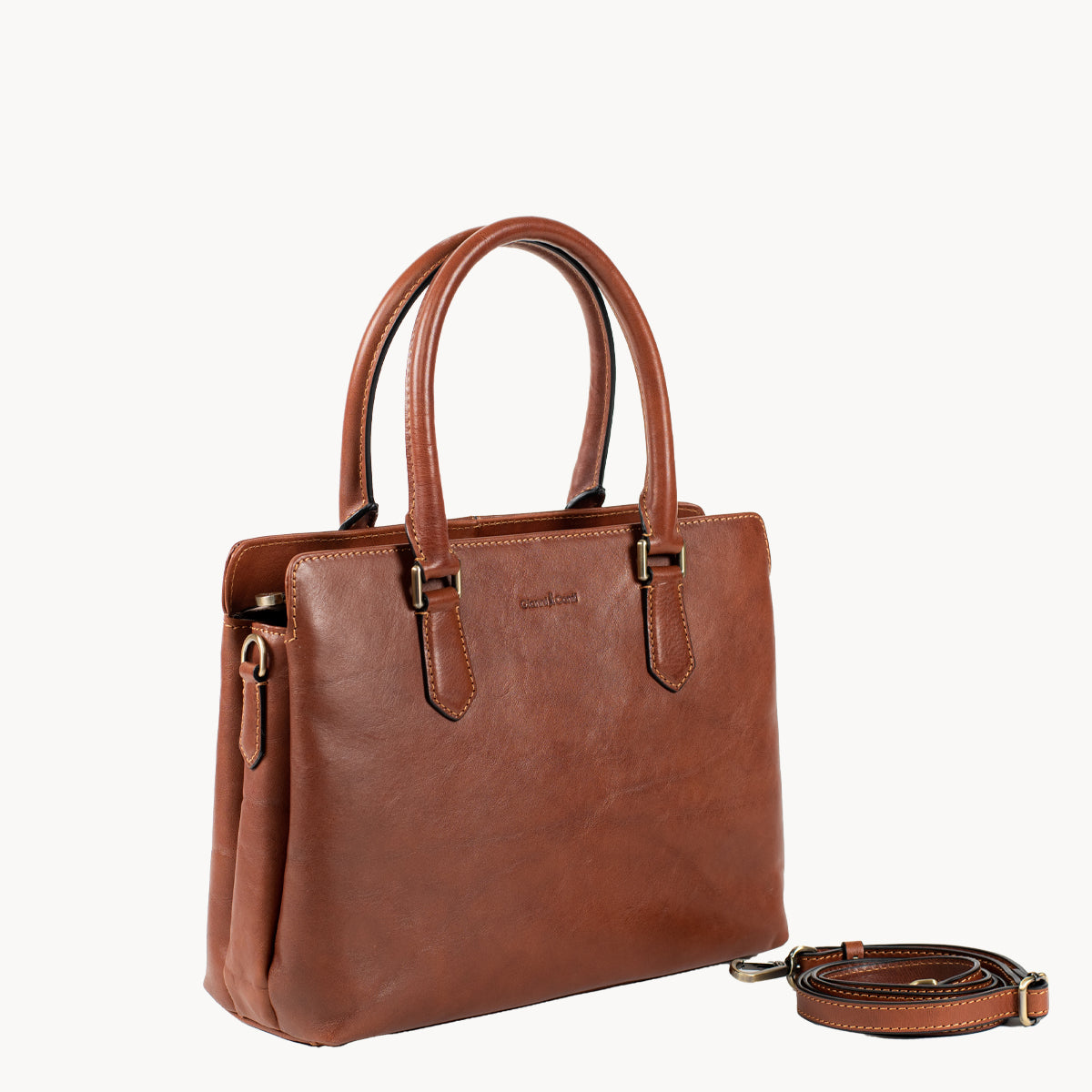Tan leather handbag with a strap on a white background