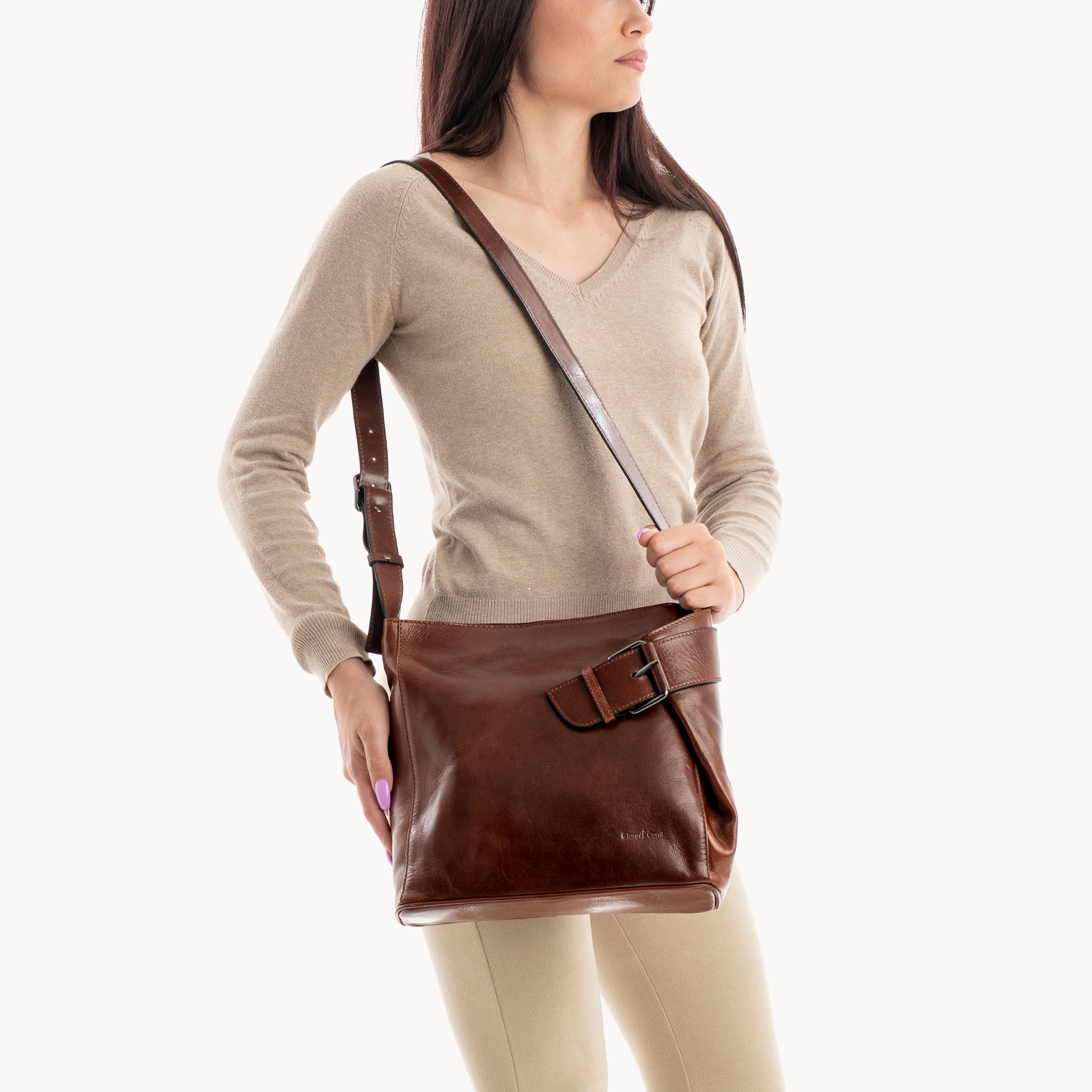 Woman carrying a brown leather crossbody bag on a white background