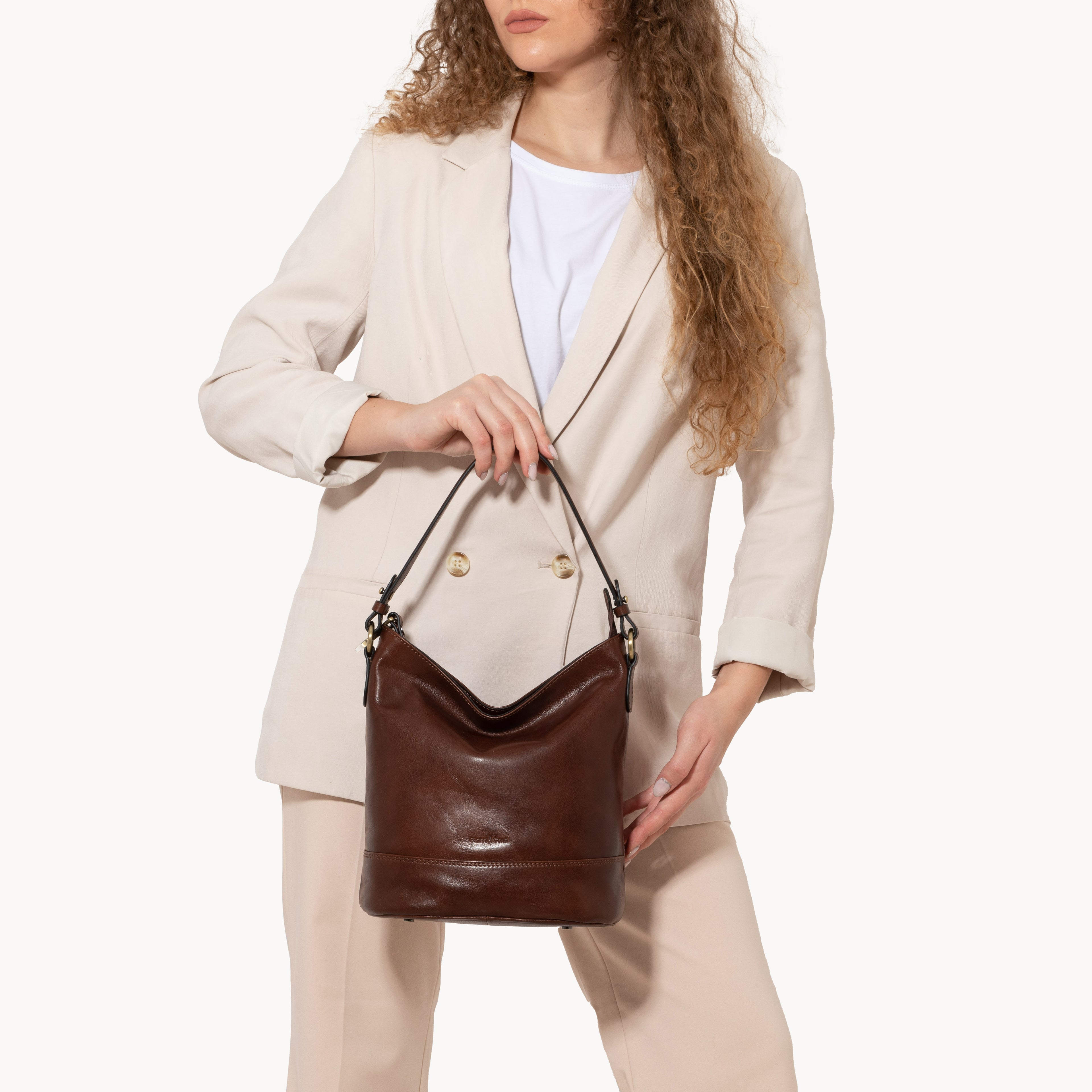 Woman holding a brown leather handbag against a white background