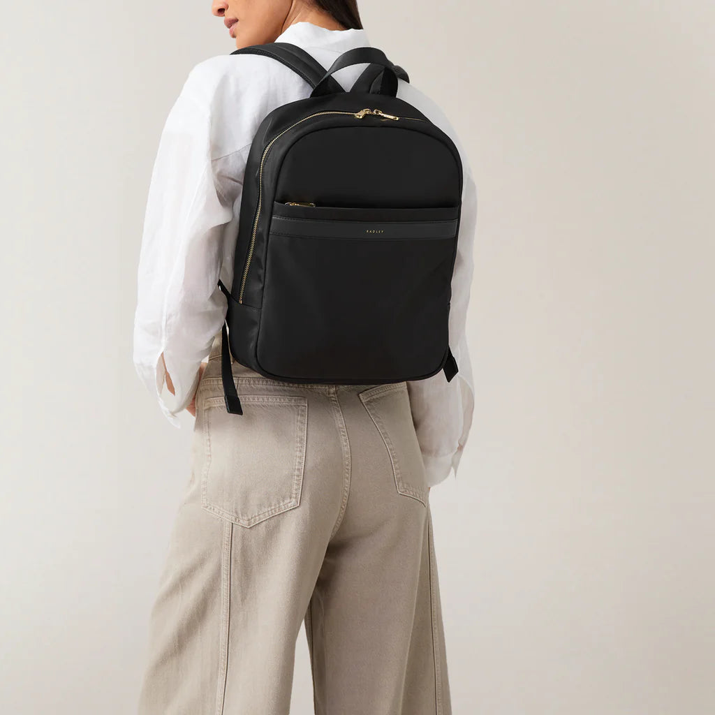 Person wearing a black backpack on a plain background