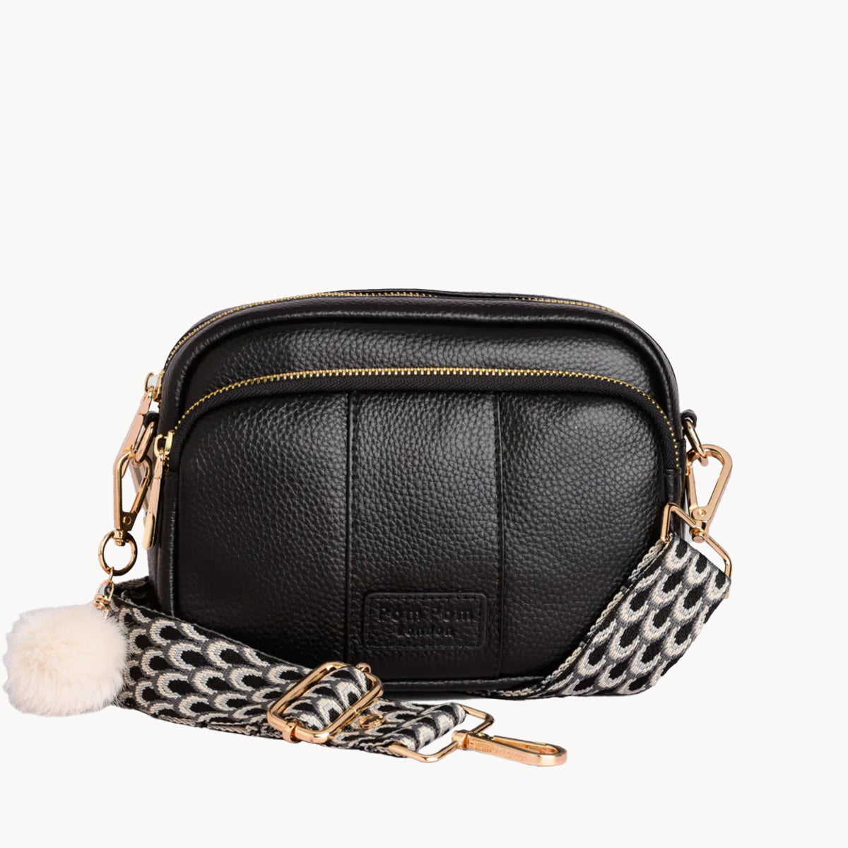 Black leather crossbody bag with a patterned strap on a white background