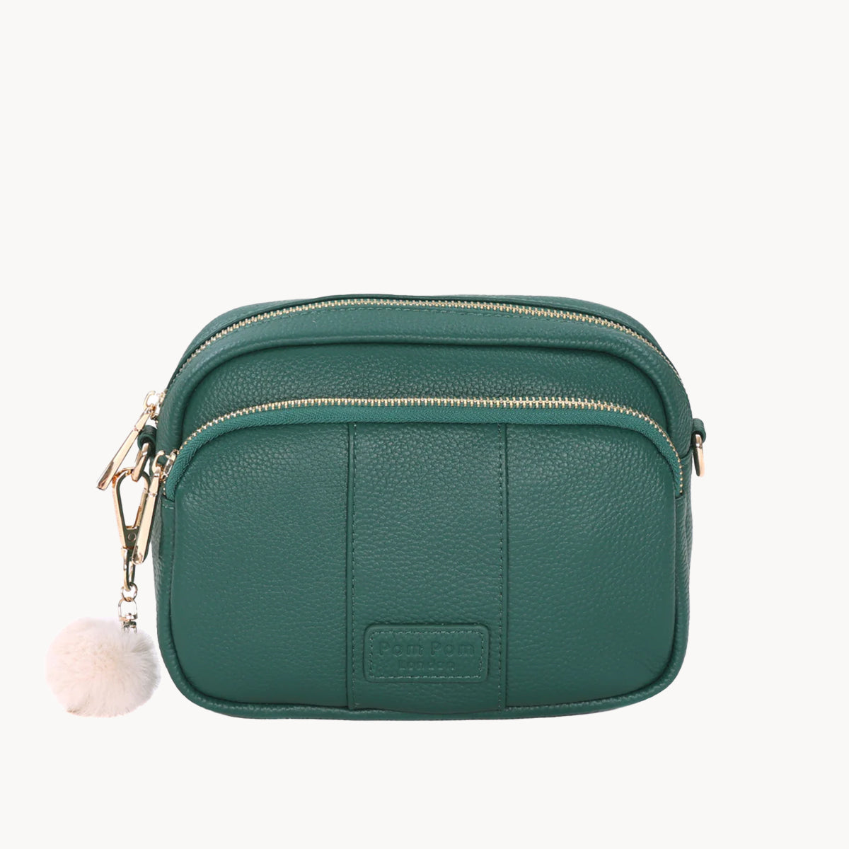 Green crossbody bag with a fluffy pom-pom charm on a white background