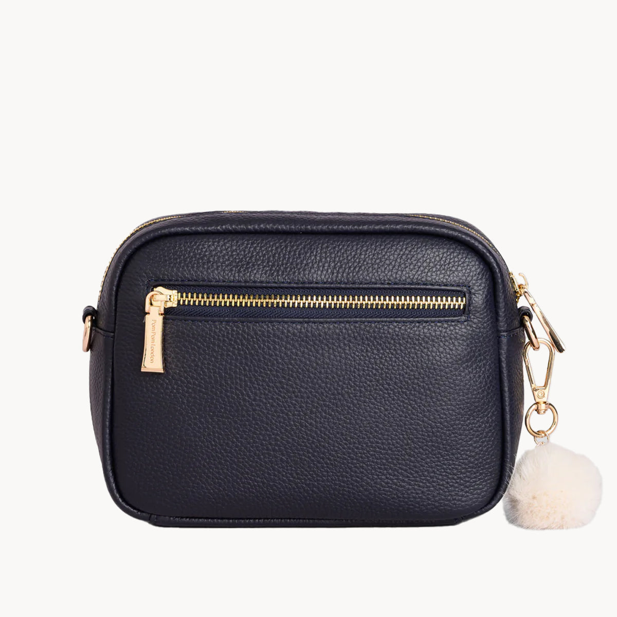 Black crossbody bag with gold zipper and white pom-pom charm on a white background