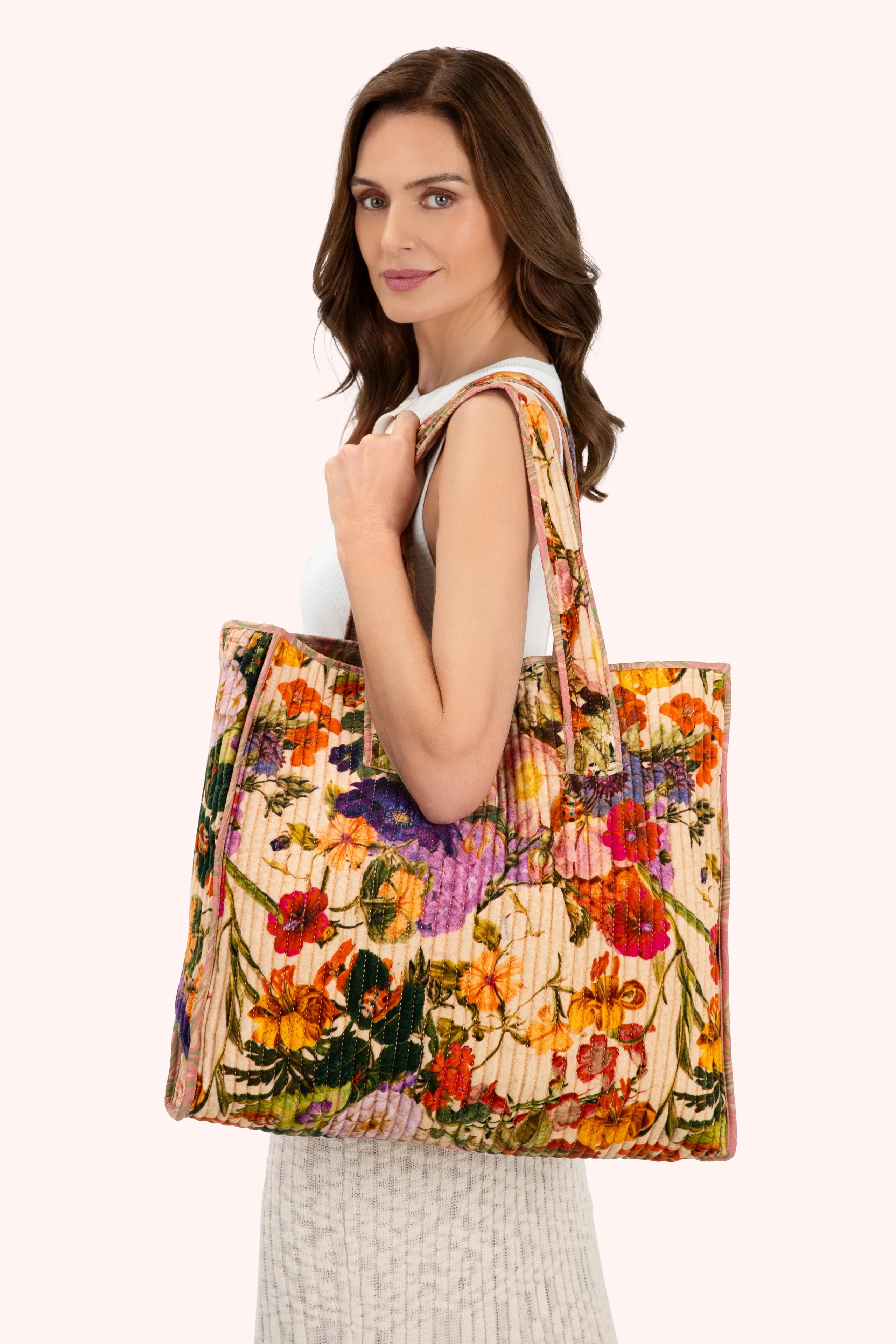 Woman holding a colorful floral tote bag against a white background