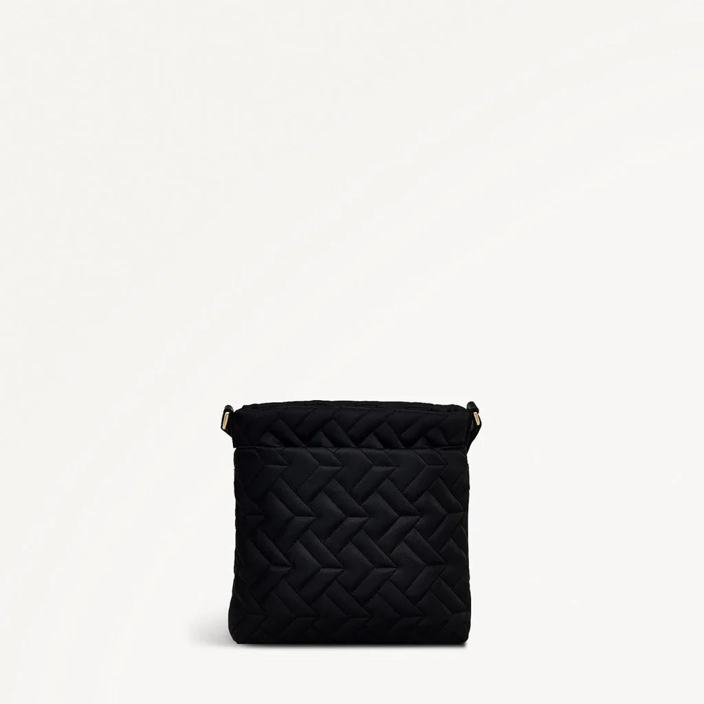 Black quilted handbag on a light beige background