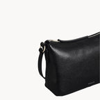 Black leather handbag with a strap on a white background