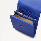 Blue leather wallet with gold zipper and button on a light gray background