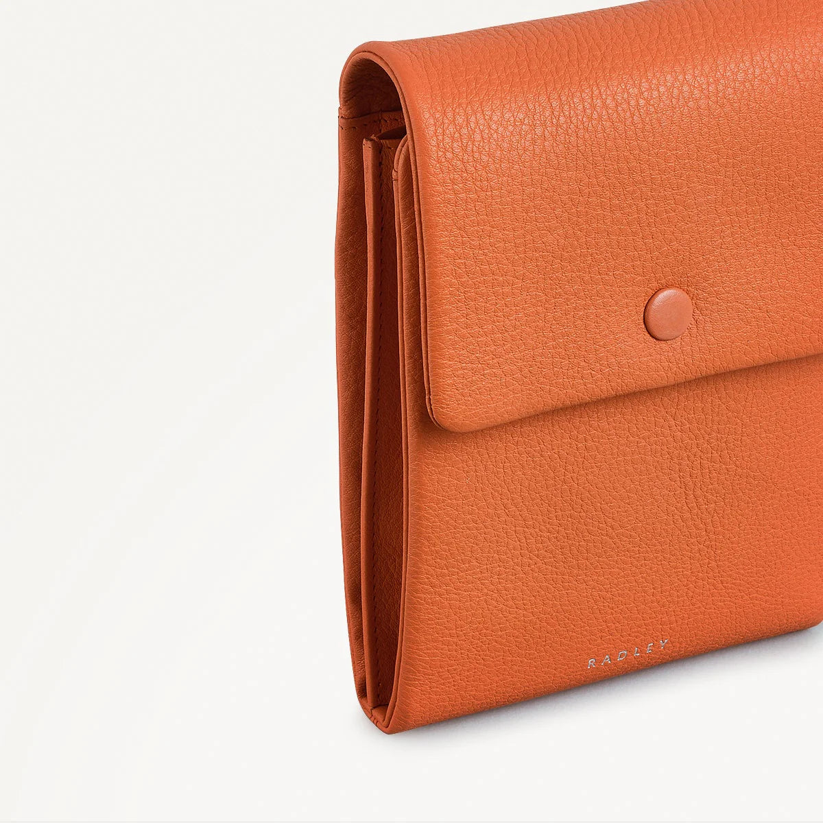 Orange leather clutch bag on a light gray background