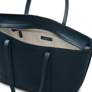 Close-up of a teal blue handbag with a visible brand logo on a white background