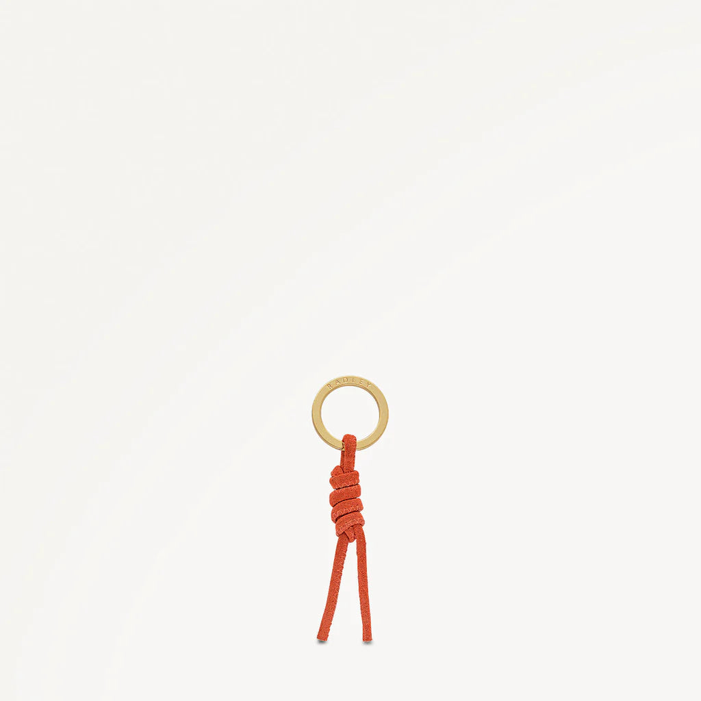 Small keychain with a gold ring and orange cord on a white background