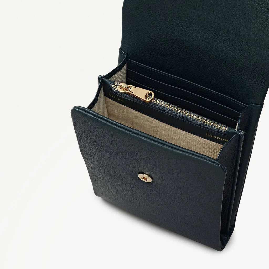 Black leather handbag with gold zipper and clasp on a light gray background