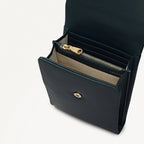 Black leather handbag with gold zipper and clasp on a light gray background