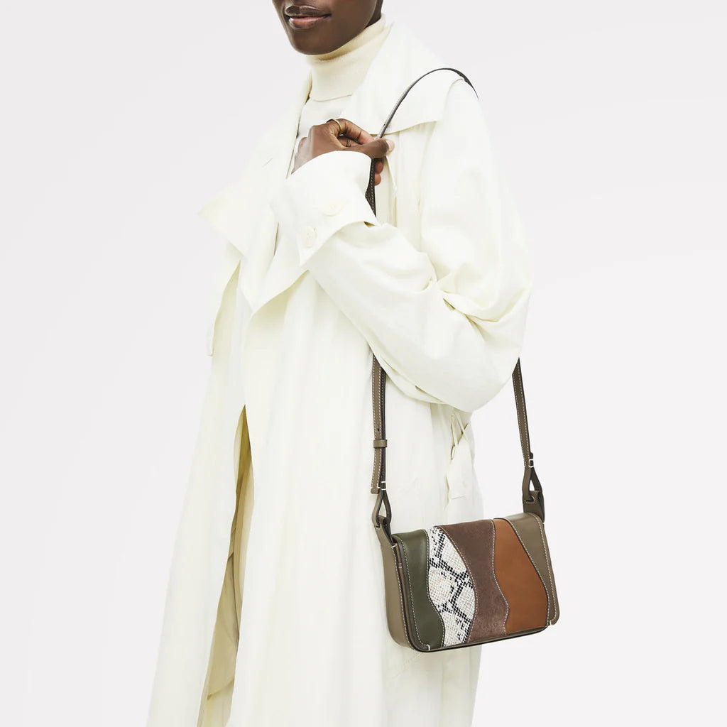 Person wearing a white outfit with a brown and beige handbag on a white background
