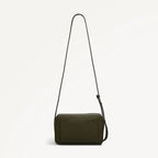 Green leather crossbody bag with a strap on a light gray background