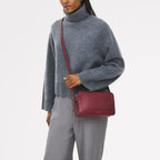 Person wearing a gray sweater and holding a red handbag on a white background