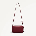 Red handbag with a strap on a light beige background