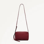 Red handbag with a strap on a light beige background