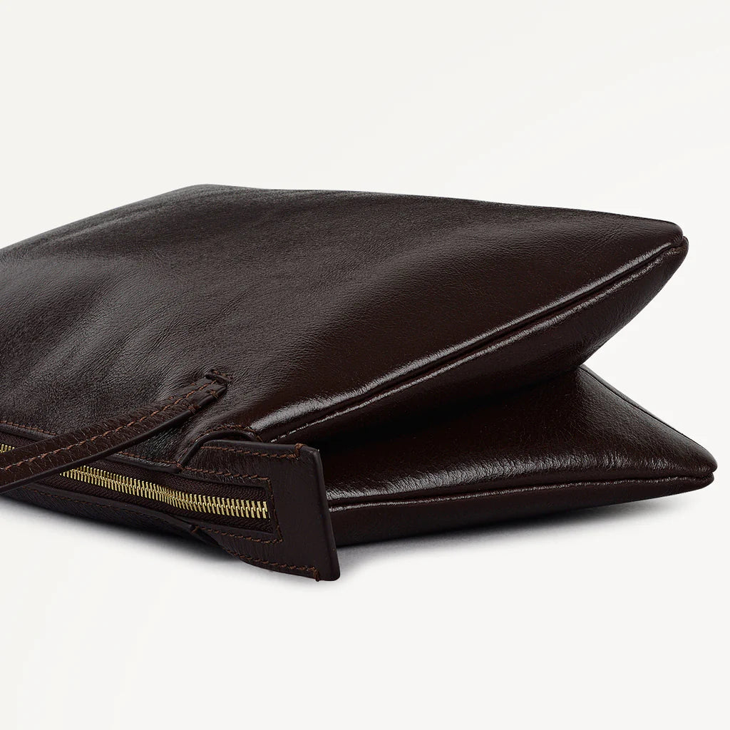 Brown leather clutch bag with gold zipper on a white background