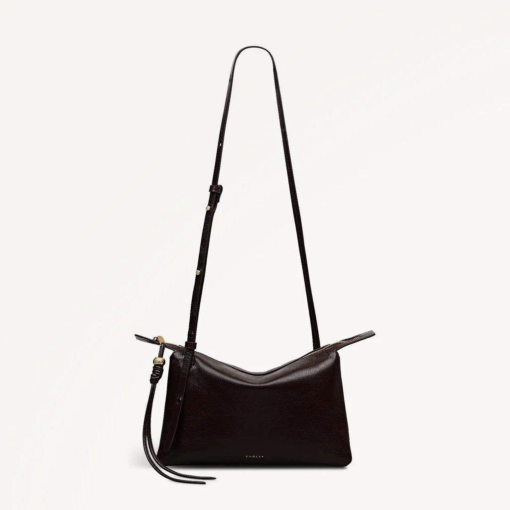 Black handbag with a long strap on a light gray background