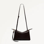 Black handbag with a long strap on a light gray background