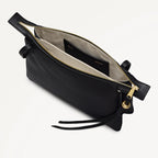 Black leather handbag with gold zipper on a light gray background