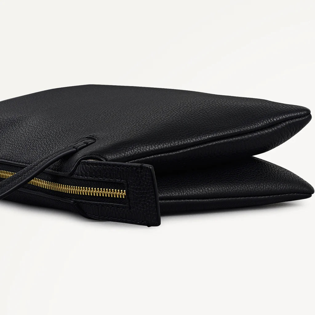 Black clutch bag with a gold zipper on a light gray background