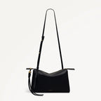 Black shoulder bag with a strap on a light gray background