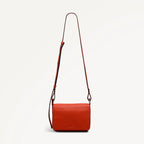 Red handbag with a strap on a light gray background