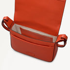 Open red leather handbag on a light gray background
