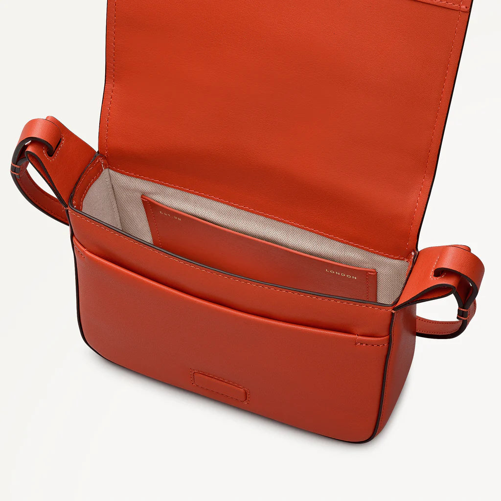 Open red leather handbag on a light gray background