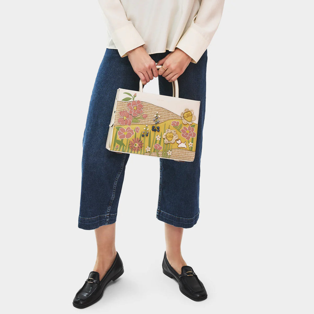 Person holding a floral-patterned handbag against a white background