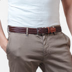 Person wearing a brown belt with a white shirt and beige pants on a light gray background