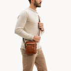 Man wearing a brown leather crossbody bag on a white background