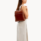 Woman carrying a brown leather backpack on a white background