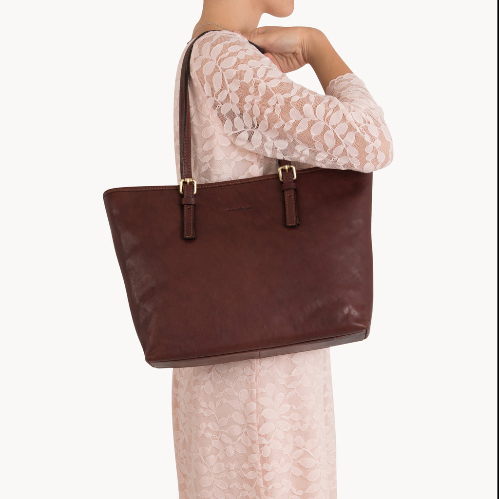 Woman holding a brown leather tote bag on a white background