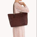 Woman holding a brown leather tote bag on a white background