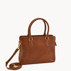 Tan leather handbag with a matching strap on a white background