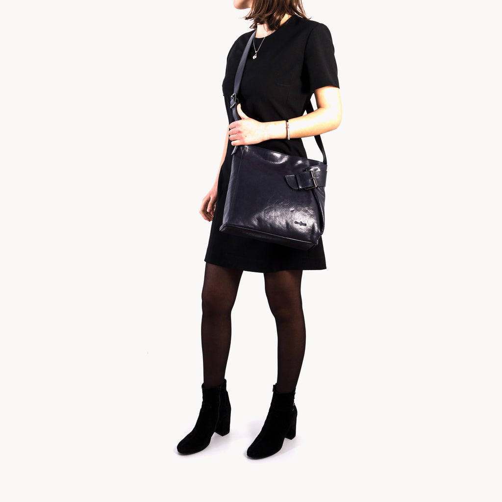 Person wearing a black leather handbag on a white background