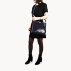 Person wearing a black leather handbag on a white background