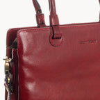 Close-up of a red leather handbag with visible brand name on a white background
