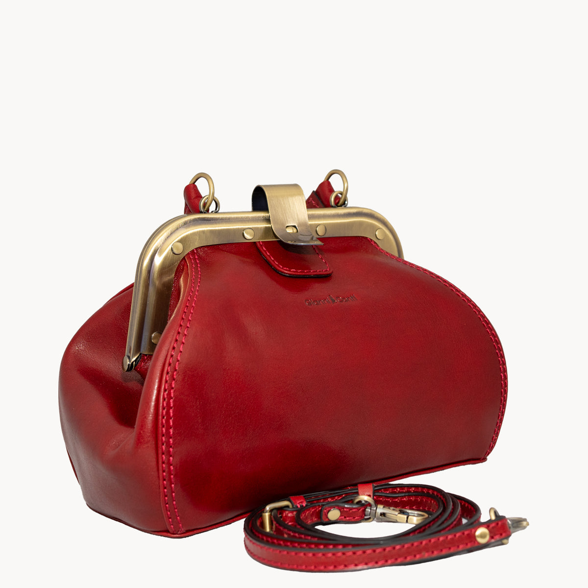 Red Gladstone style bag with metal clip opening and grad handle with detachable long strap.