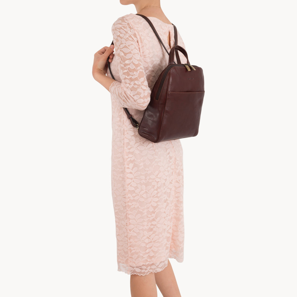 Person wearing a brown leather backpack on a white background