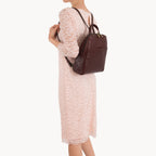 Person wearing a brown leather backpack on a white background