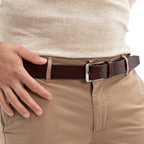 Person wearing a brown belt with a white shirt and beige pants.
