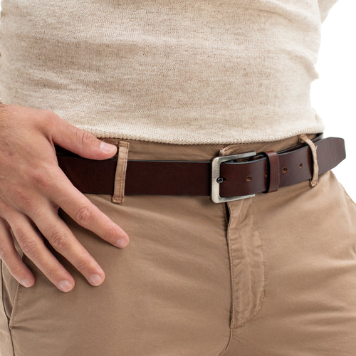 Person wearing a brown belt with a white shirt and beige pants.